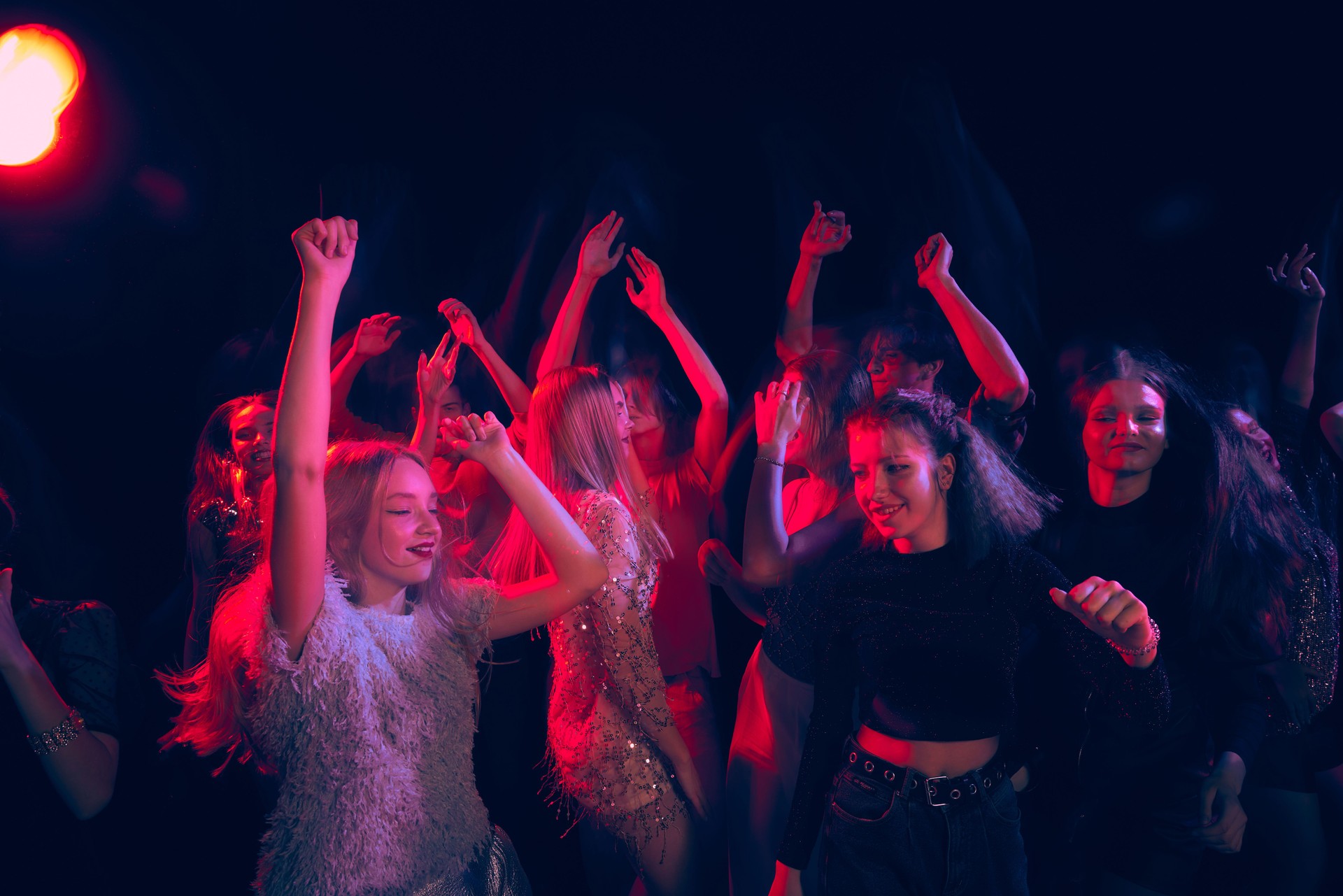 Group of young people attending party, dancing, having fun over dark background in neon light. Hippie generation