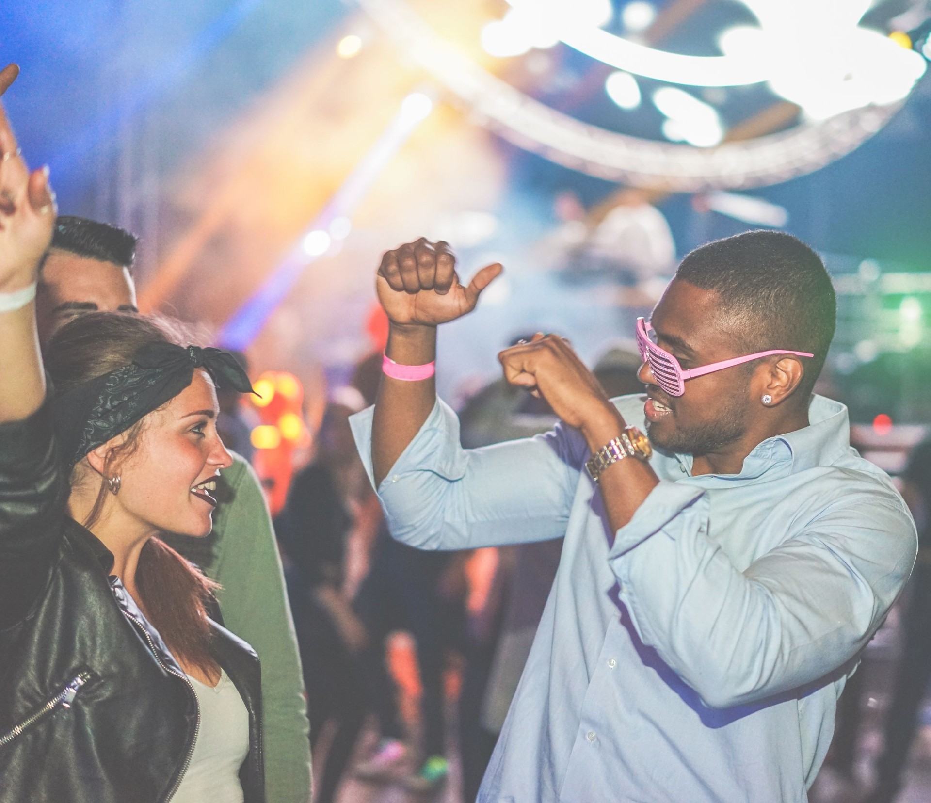 Young friends dancing at party in night club - Diverse culture people enjoying weekend nightlife with original laser lights colors in background - Youth concept - Soft focus on black man - Warm filter